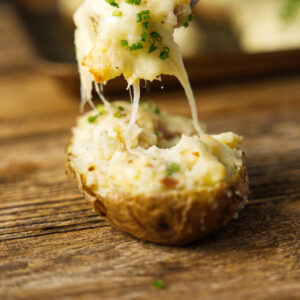 A fork scooping twice baked potatoes from a potato skin.