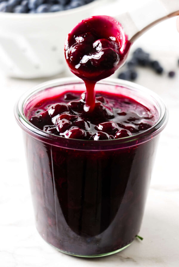 Blueberry sauce drizzling from a spoon.