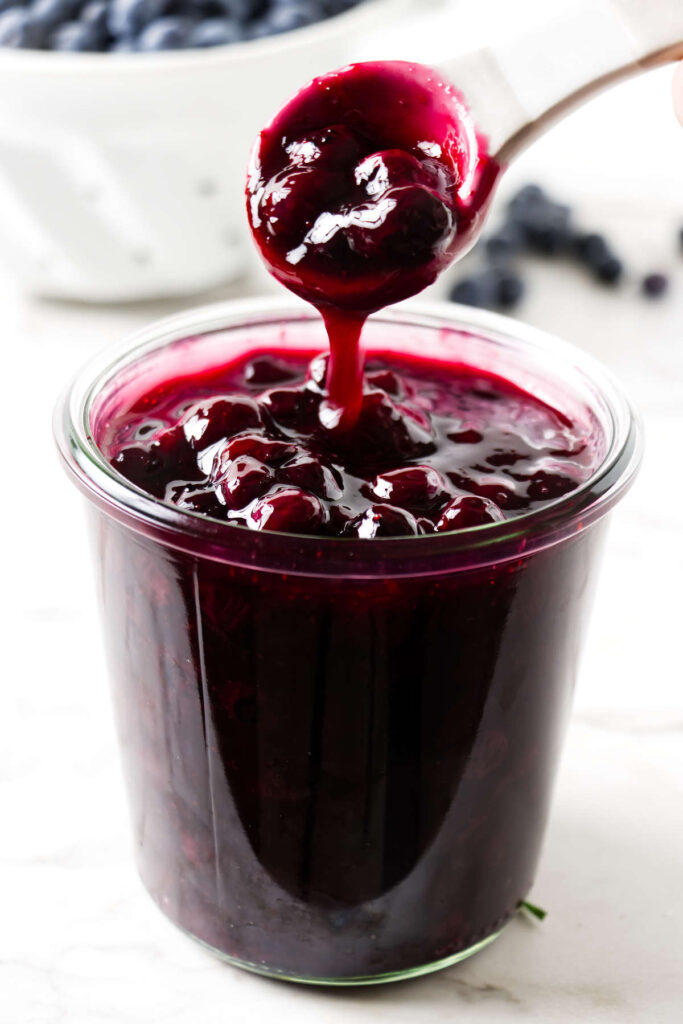Blueberry sauce drizzling from a spoon.
