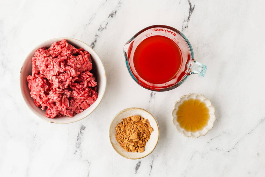 Ingredients for ground beef taco meat with tomato juice, taco seasoning, and vinegar.