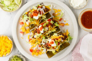 Ground beef taco plate with lettuce, cheese, sour cream, salsa, and guacamole.