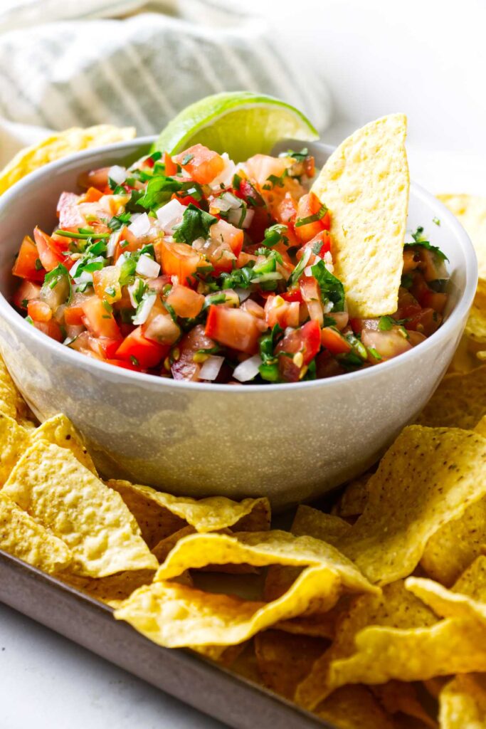 A chip in a bowl of Mexican salsa fresca.