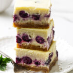 Lemon blueberry cheesecake bars stacked on top of each other.