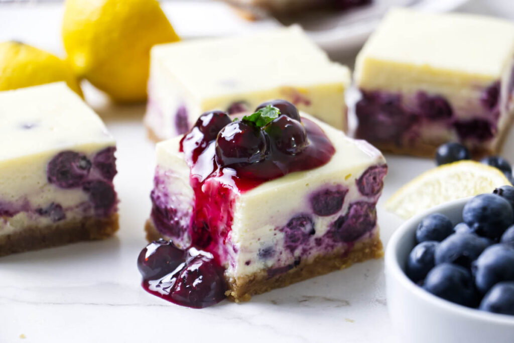 Creamy blueberry lemon cheesecake bars on a serving plate.