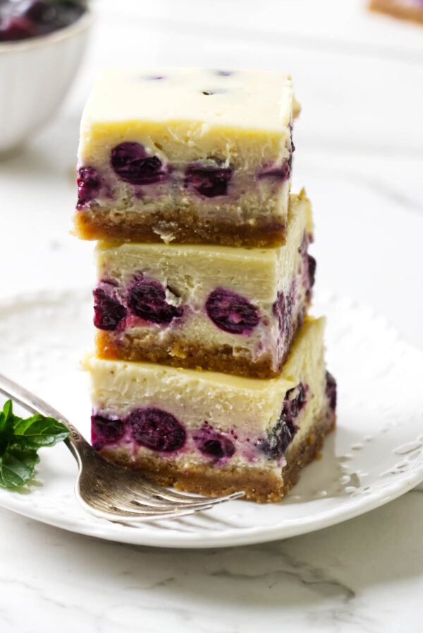 Lemon blueberry cheesecake bars served with fresh blueberries.