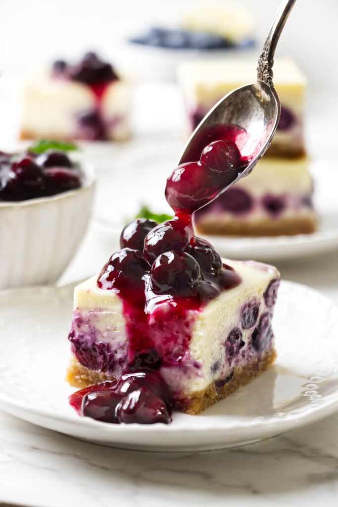 Blueberry cheesecake bars sliced into squares with a graham cracker crust.