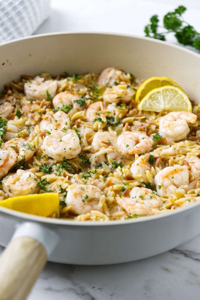 Lemon shrimp and orzo in a skillet with Parmesan and herbs.