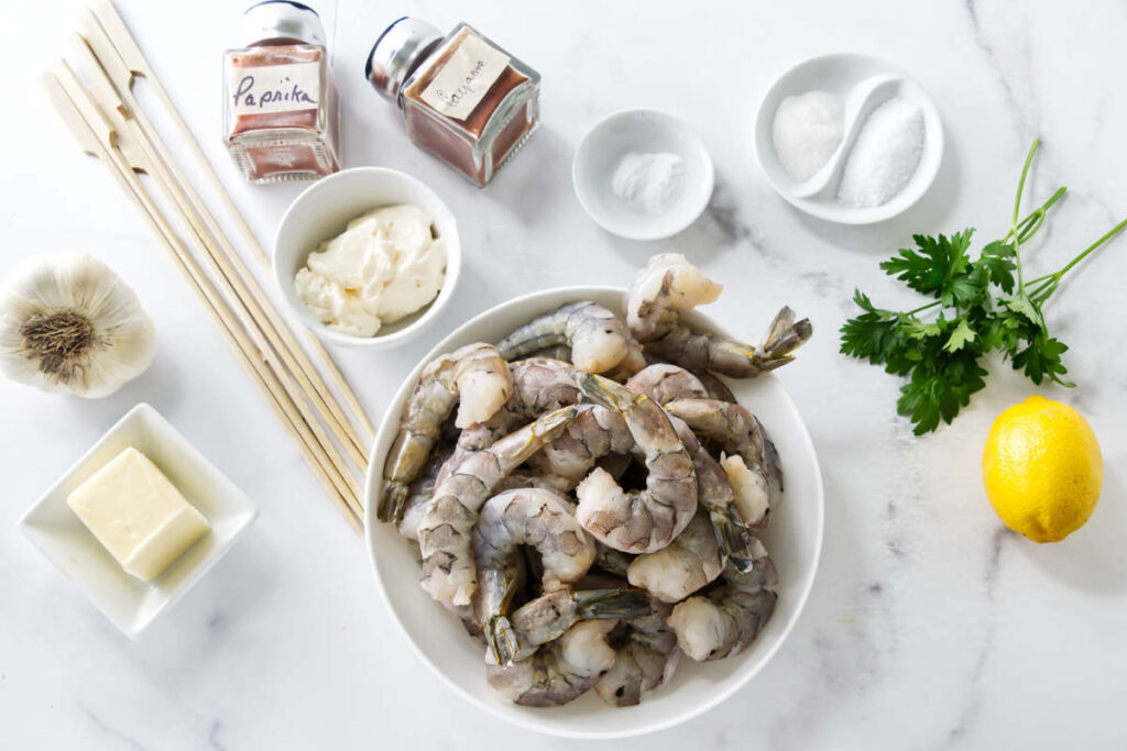 Ingredients for spicy grilled shrimp skewers with shrimp, garlic, lemon, parsley, and spices.