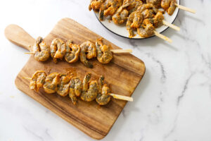 Marinated shrimp threaded onto bamboo skewers before grilling.