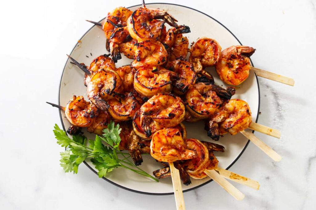 Spicy grilled shrimp recipe served on skewers with fresh parsley.