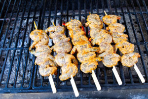 Raw marinated shrimp skewers arranged on the grill before cooking.