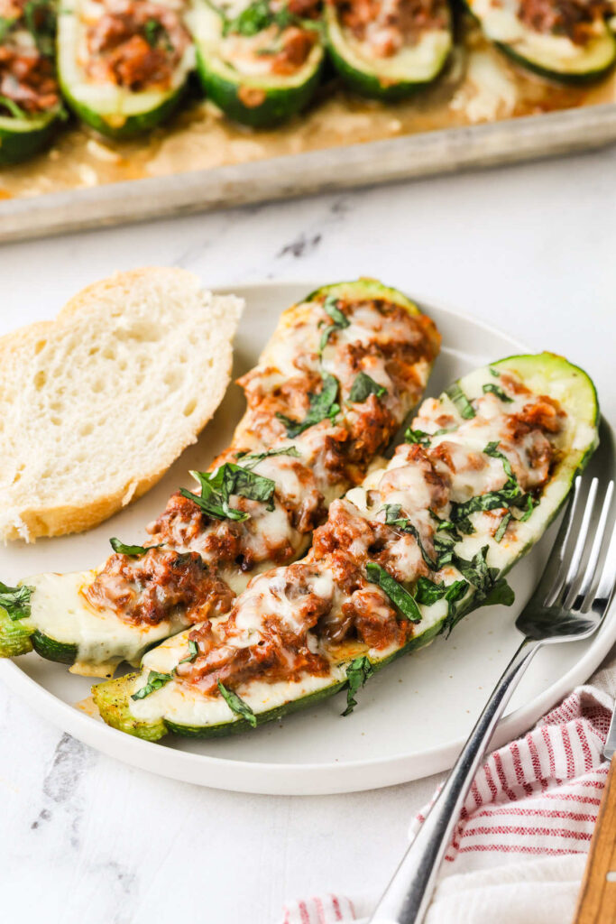Stuffed zucchini served on a plate with garlic bread.