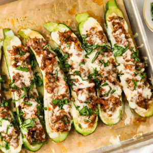 Tray of zucchini stuffed with browned meat sauce and melted mozzarella.