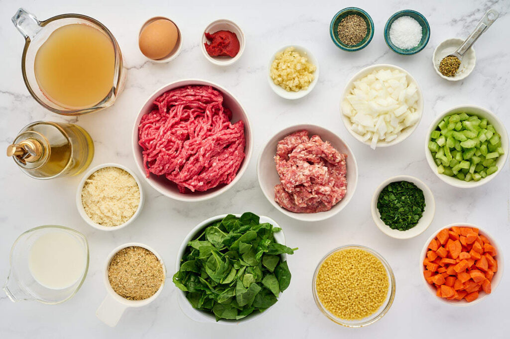 Ingredients arranged for homemade Italian wedding soup, including broth, vegetables, greens, pasta, and meatball ingredients.