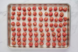 Rows of small raw meatballs ready to bake for Italian wedding soup.