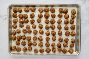 Baked Italian wedding soup meatballs arranged on a metal baking sheet.