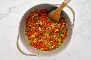 Diced onion, carrots, celery, and garlic cooking together in a pot for wedding soup.