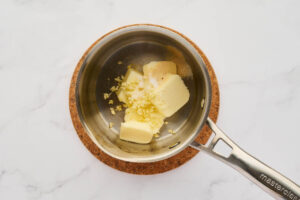 Butter, minced garlic, and seasonings melting in a saucepan for garlic knot bread.
