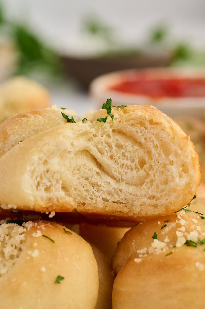Torn garlic knot showing the soft bread texture inside.