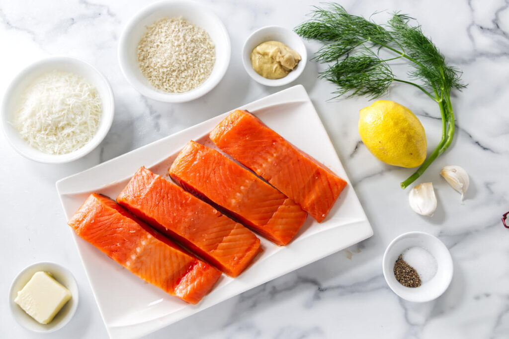 Ingredients for baked salmon with panko crust, including salmon, Parmesan, panko, Dijon mustard, lemon, garlic, dill, butter, salt, and pepper.