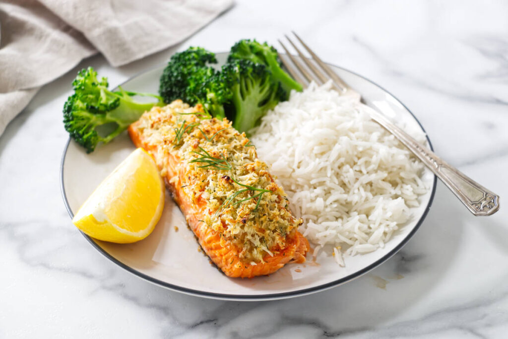 Baked Parmesan salmon served with white rice, broccoli, and lemon.