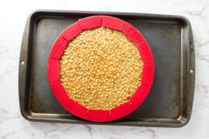 Round pan of uncooked pine nut filling in tart pan.