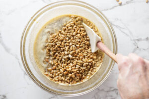Stirring pine nuts into a tart filling batter.