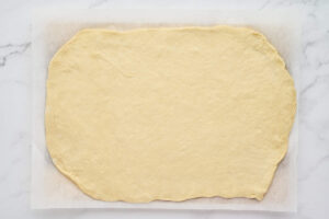 Pizza dough rolled into a rectangle on parchment paper for homemade stromboli.