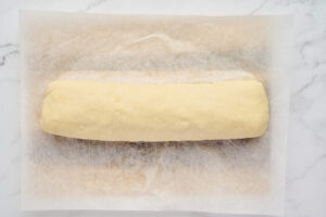 Rolled and sealed stromboli log resting on parchment paper before baking.