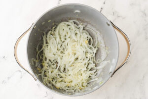 Sliced onions cooking in a pot for the miso salmon ramen broth.