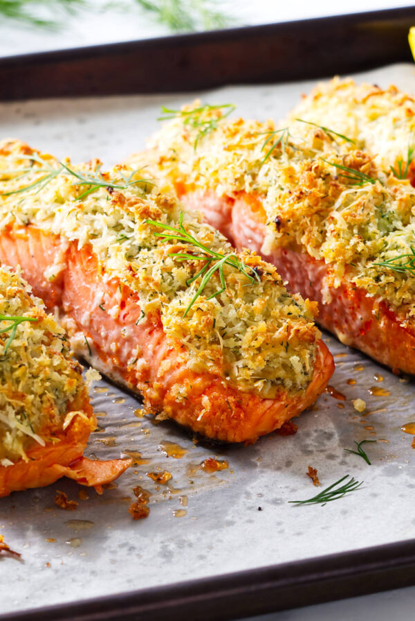 Baked salmon fillets with crispy panko crust and dill on parchment.