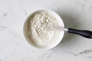 Flour and sugar whisked together for a pistachio cheesecake batter.