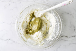 Pistachio paste being added to the cream cheese mixture for pistachio cheesecake.