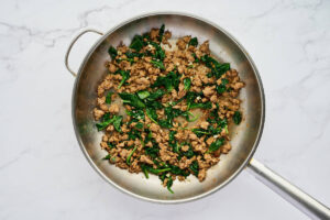 Cooked Italian sausage and spinach filling in a skillet with garlic.