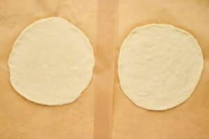 Fresh spinach added to browned Italian sausage in a skillet for calzone filling.