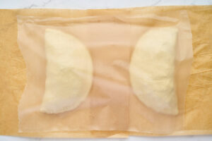 Two assembled calzones covered while they rest before baking.