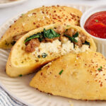Close-up of a baked sausage ricotta calzone cut open to show the cheesy filling.