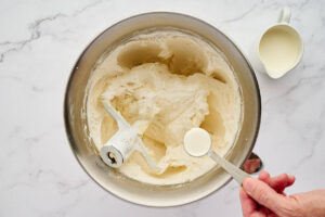 Liquid being poured from a measuring spoon into a mixing bowl.