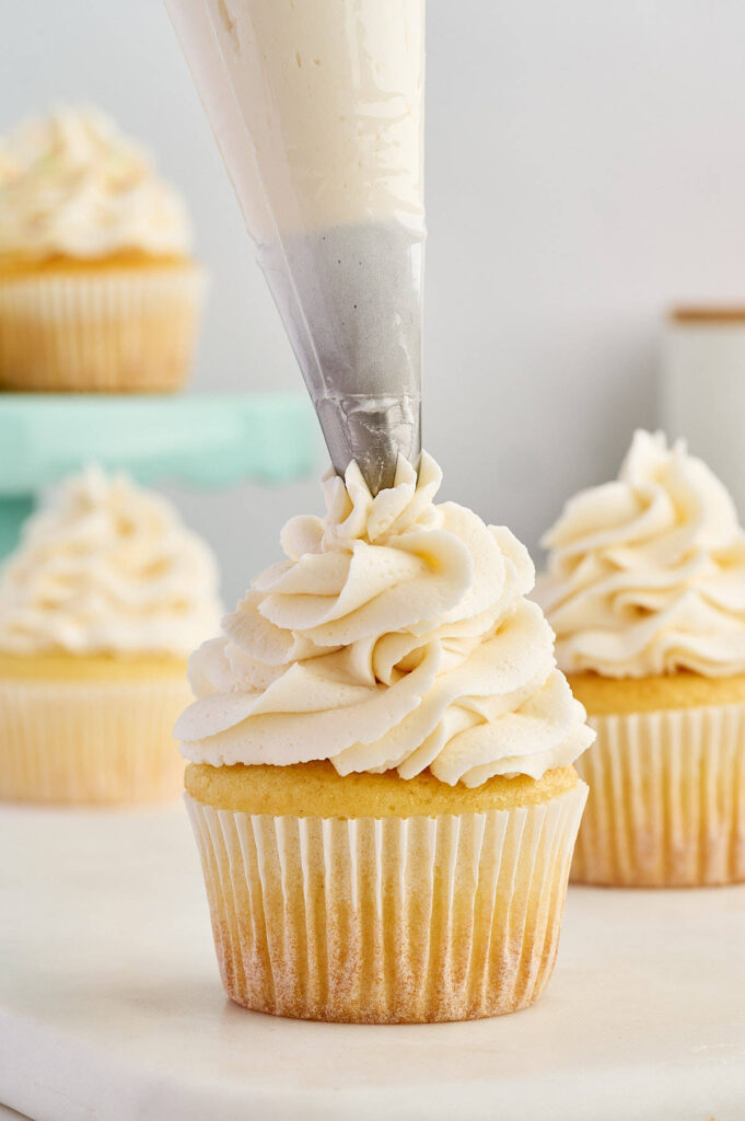 Decorative frosting swirl being piped onto a cupcake.
