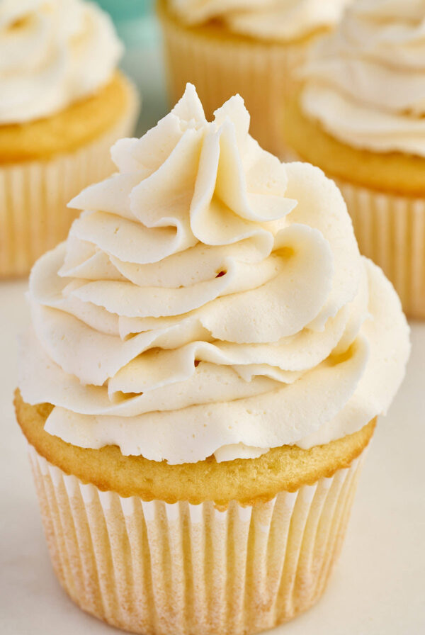 Vanilla cupcake topped with a tall swirl of white frosting.