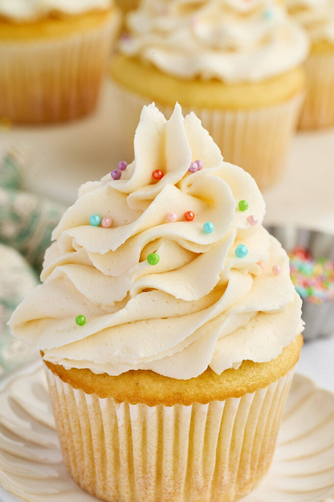 Vanilla cupcake with piped frosting and colorful sprinkles.