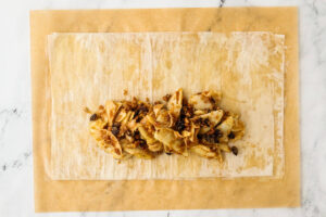 Sliced apples and raisins on a sheet of pastry.