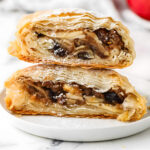 Two stacked halves of a flaky apple and raisin pastry.