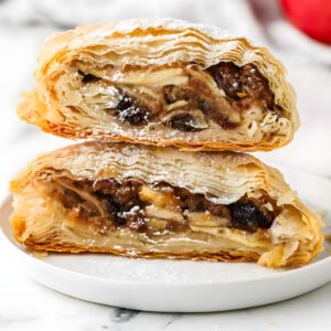 Two stacked halves of a flaky apple and raisin pastry.