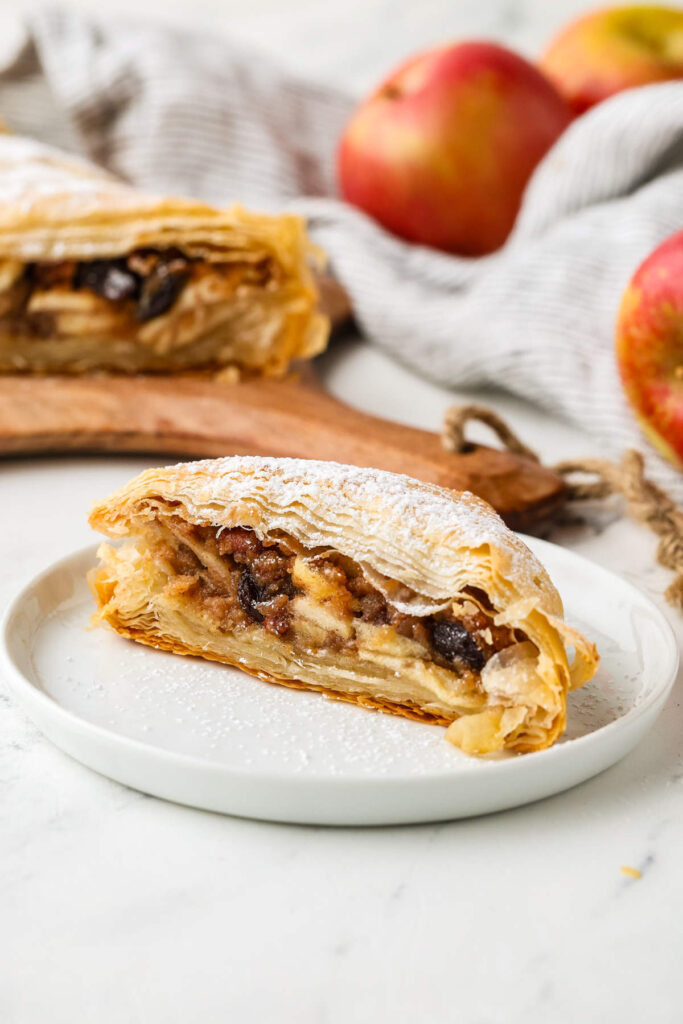 A powdered sugar-dusted slice of apple strudel on a plate.