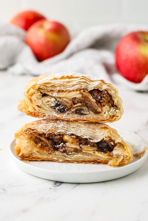 Two slices of apple strudel stacked on a small white plate.