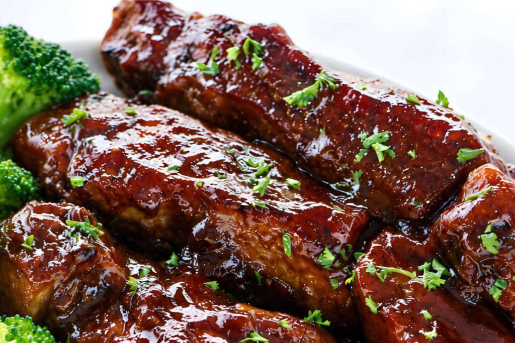 country style pork ribs in the oven Glazed barbecue ribs with parsley and a side of broccoli.