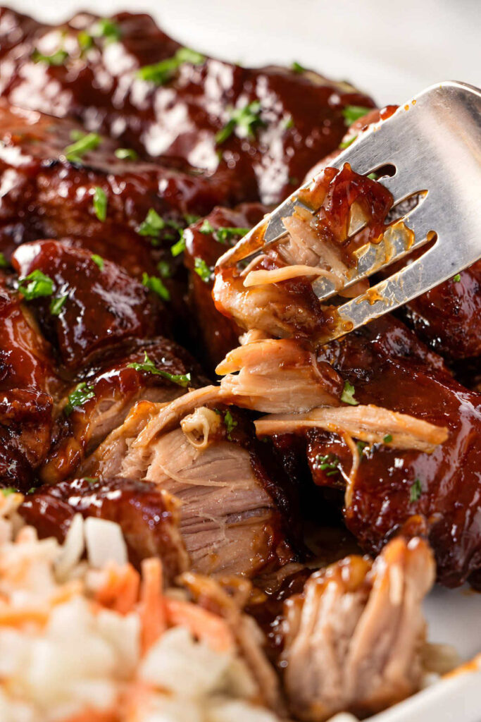Fork pulling apart saucy barbecue pork.