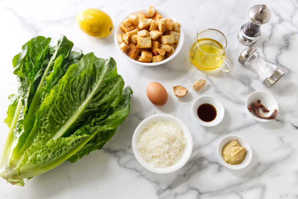 Caesar salad ingredients including romaine, croutons, egg, and dressing components.