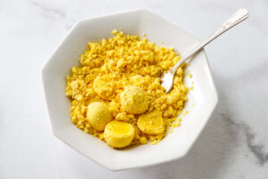 Crumbled hard-boiled egg yolks in a white bowl with a fork.